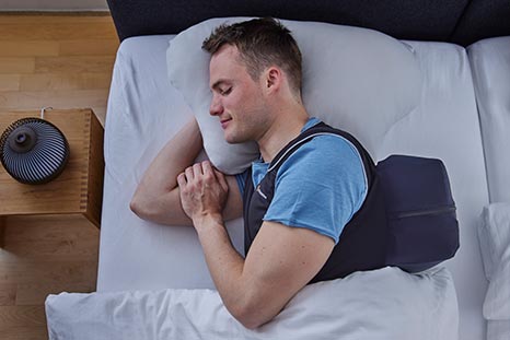 Mann schläft mit Nachtwaechter Schlafweste im Bett